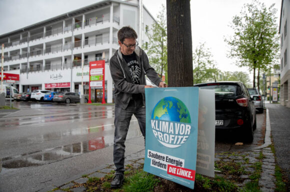 Andreas Wagner befestigt ein Plakat mit der Aufschrift "Klima vor Profit"